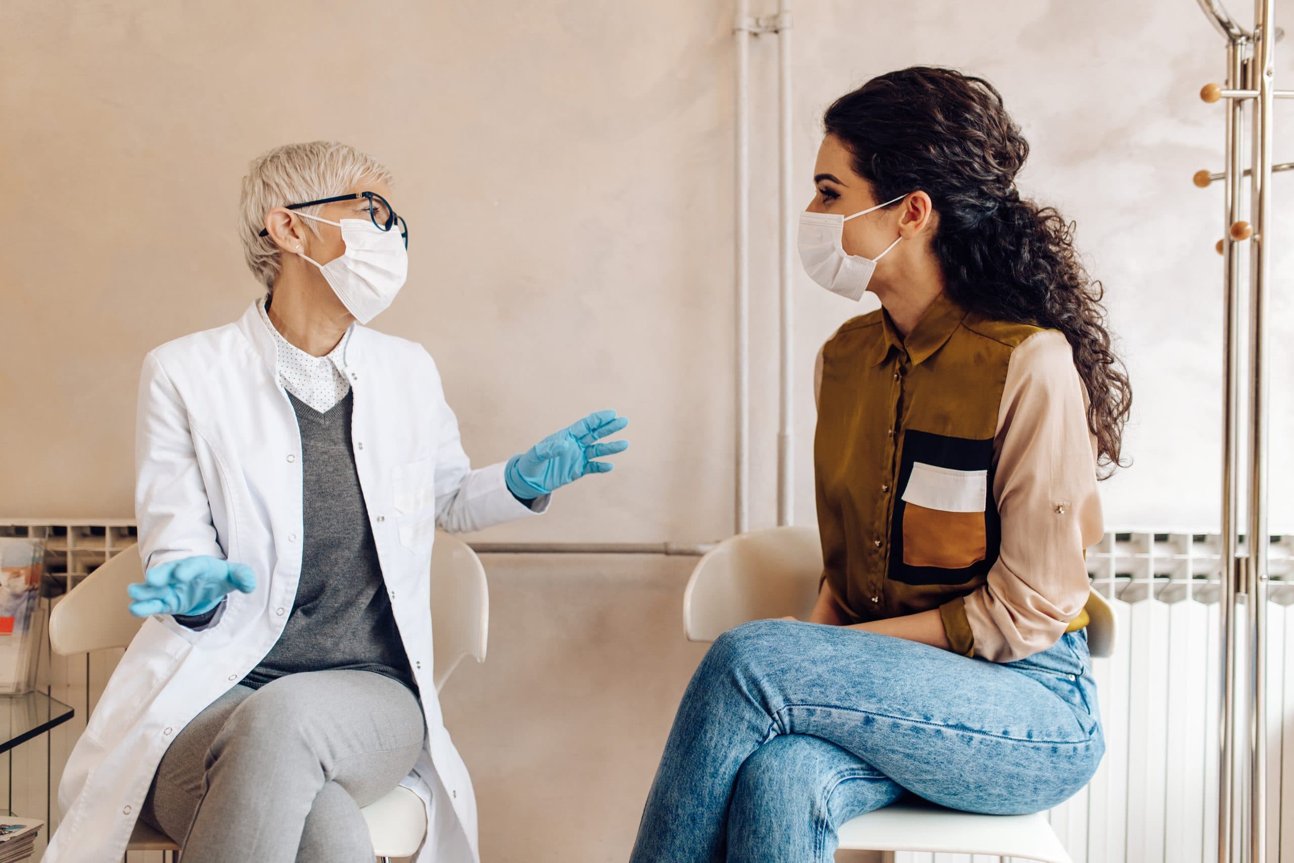 A masked female doctor talks to a masked young woman about endometriosis stages