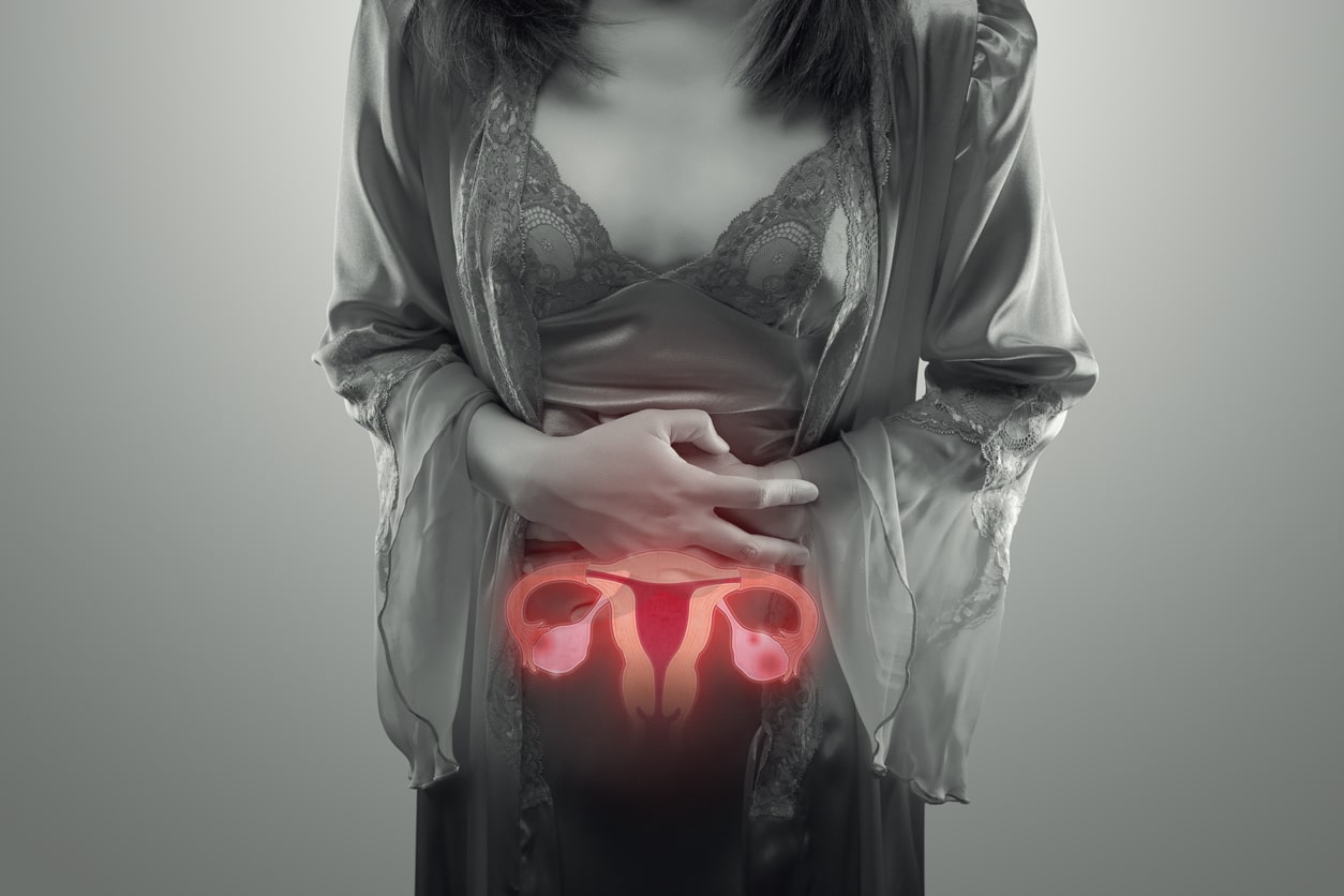A Black And White Photo Of A Woman Holding Her Stomach With A Colored Uterus Illustration.
