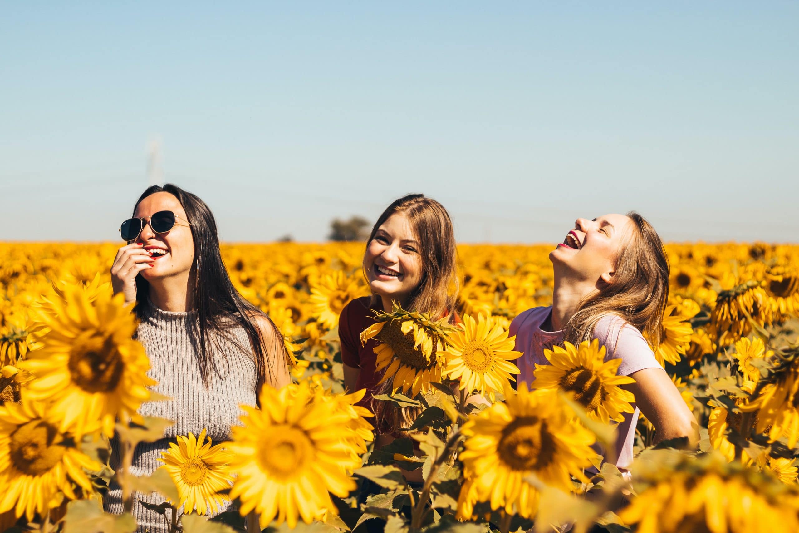 Three young women laugh in a sunflower field. Bladder control treatments can give you back a sense of freedom.