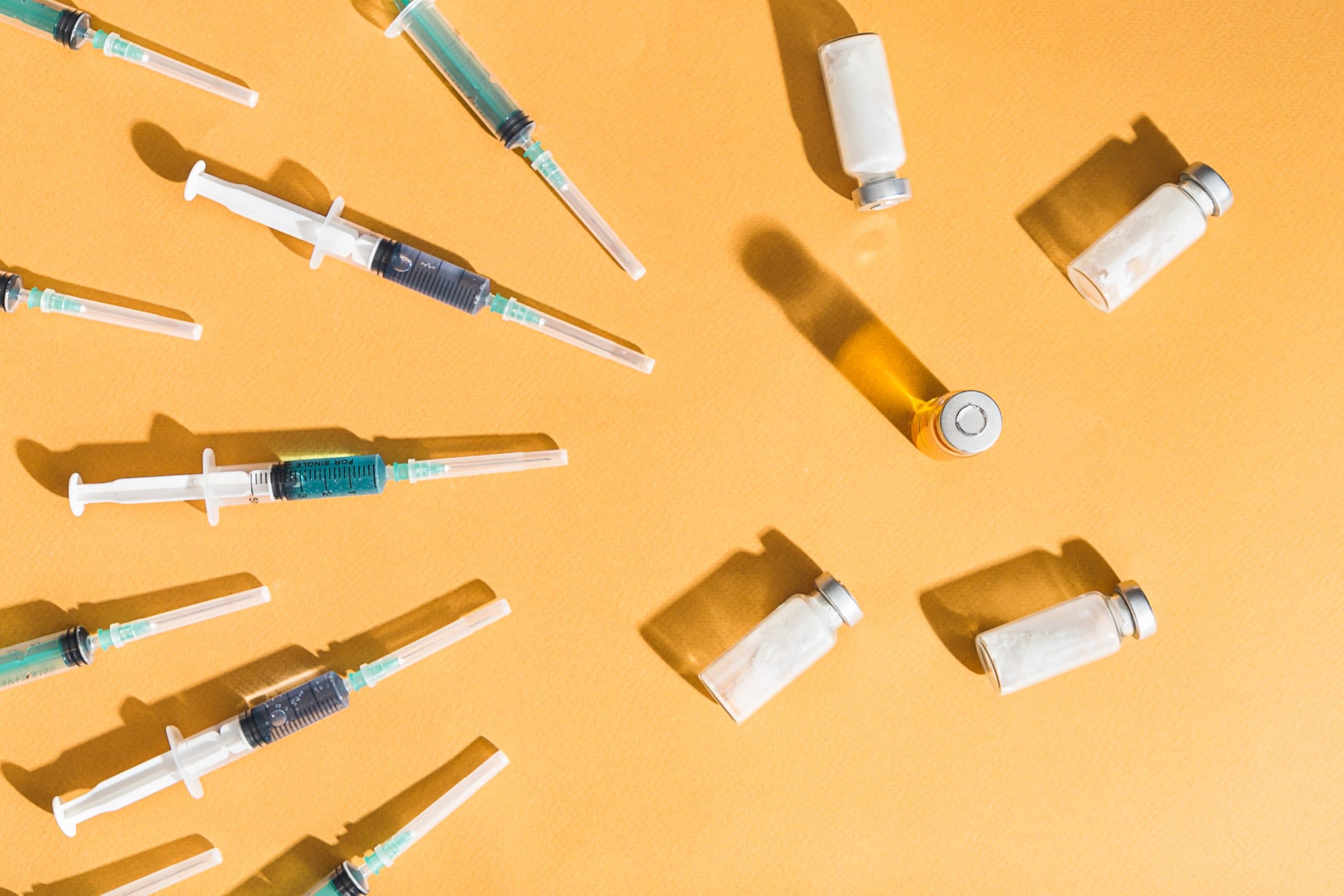 An array of Botox injection syringes and vials arranged in a starburst on a yellow background