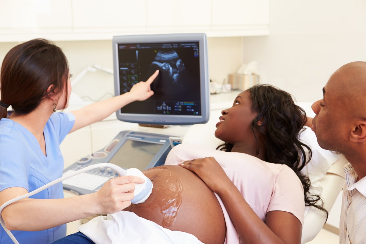 A pregnant woman with her partner having a 4d ultrasound scan of her baby.