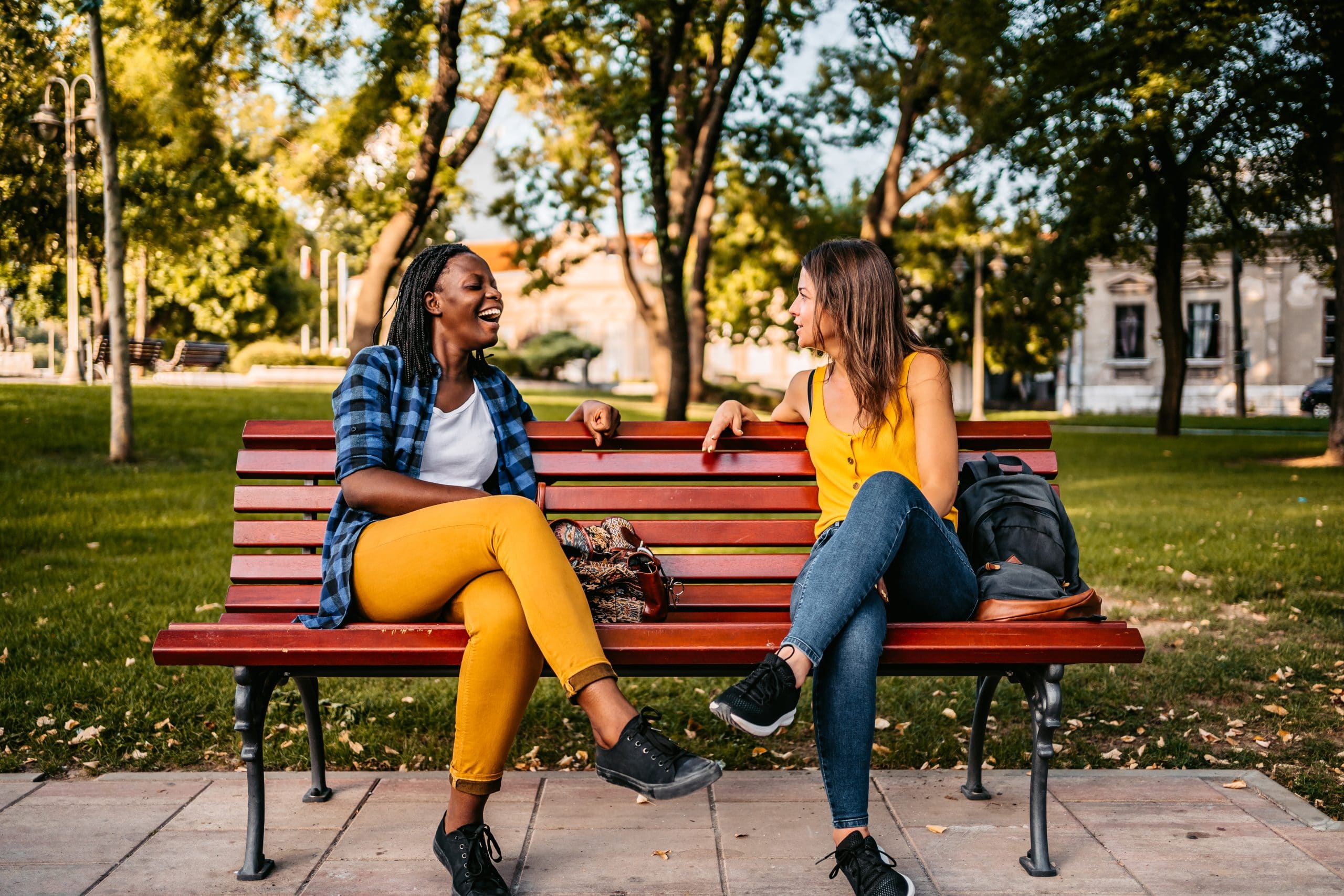 Two female friends on a park bench talk. Endometriosis vs. adenomyosis is similar with some unique characteristics.