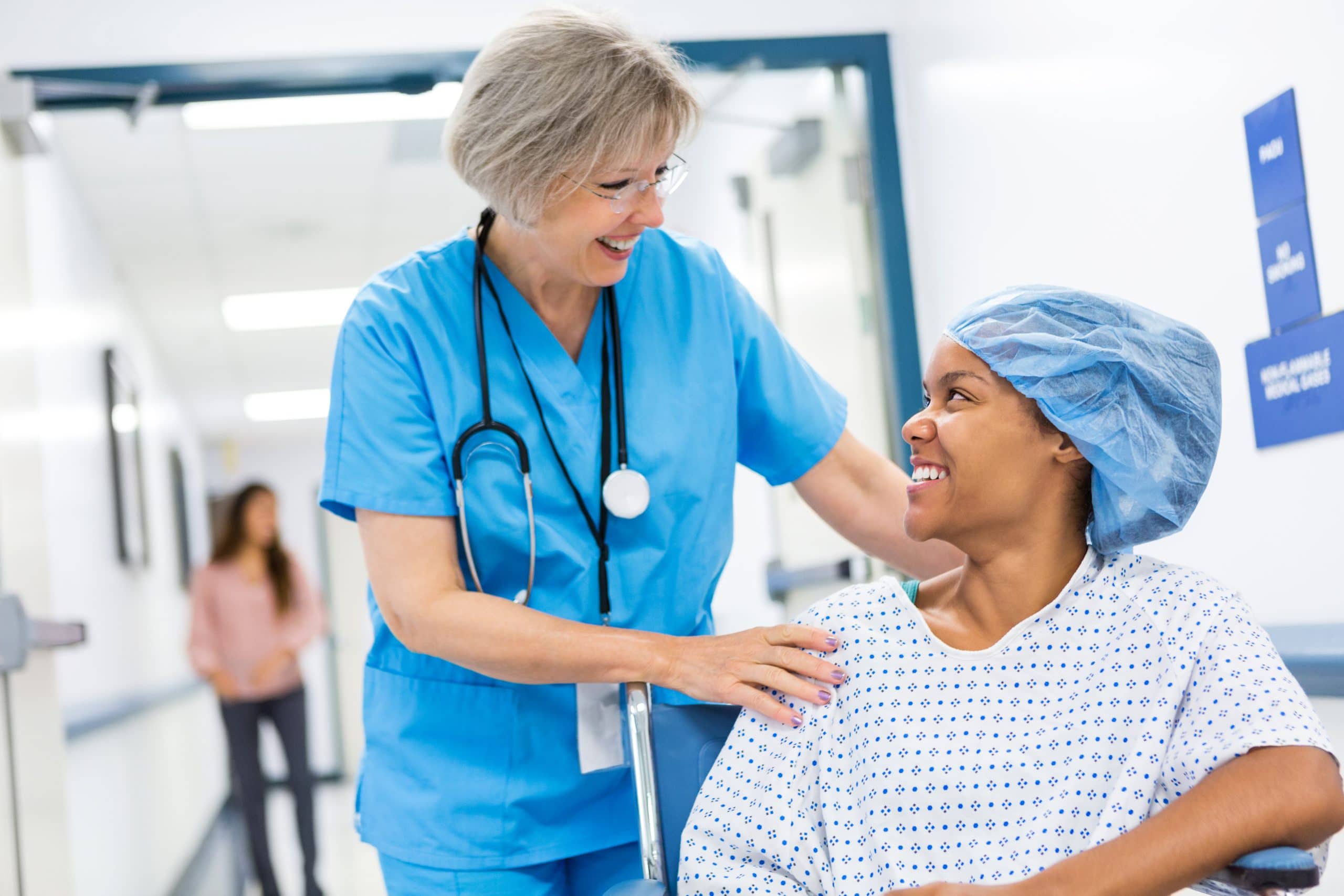 A compassionate nurse reassures a woman before for Robotic Excision Surgery for endometriosis.
