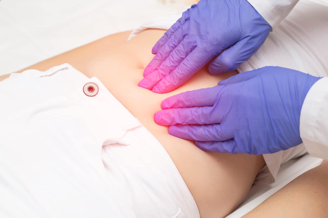 A gynecologist feeling the lower abdomen of a girl who has pain and inflammation in her abdomen
