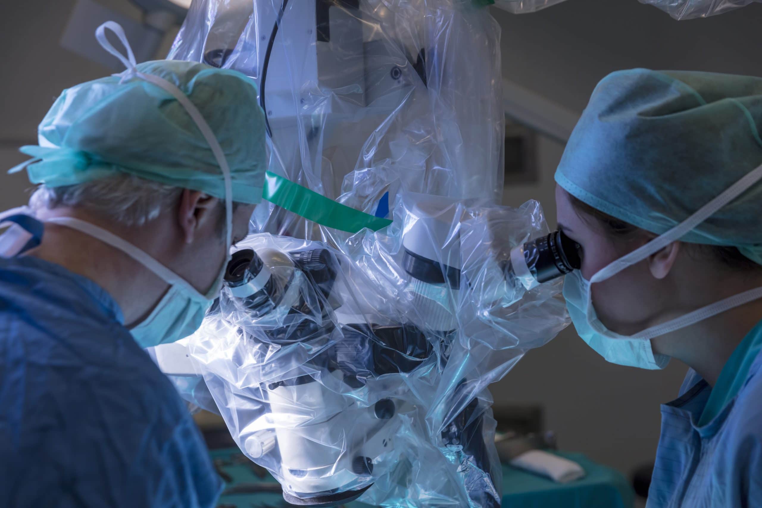 A surgeon and assistant look into an eyepiece, guiding the Da Vinci surgical system to perform a robotic hysterectomy