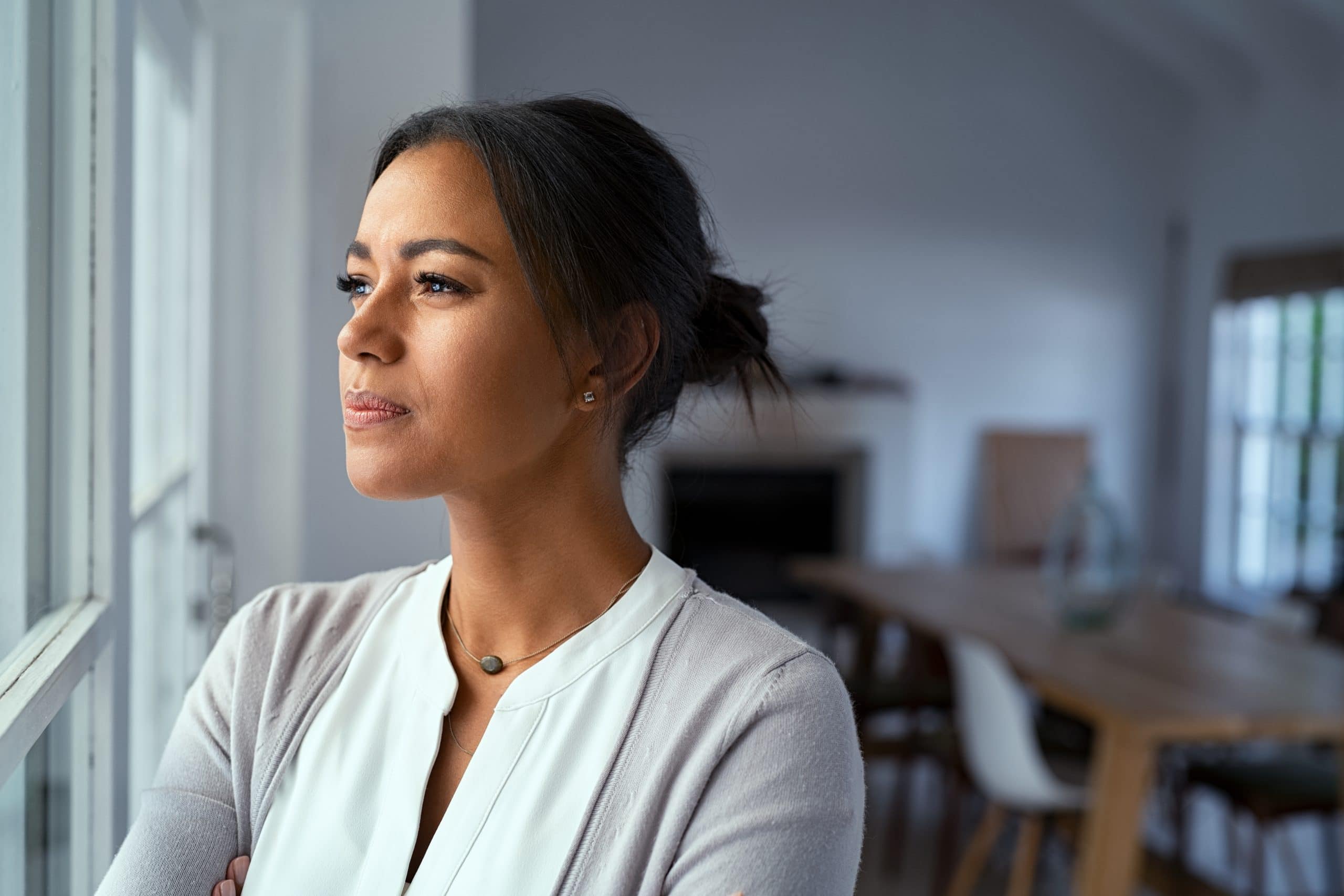 A concerned woman looks out the window. Vulvar pain and vulvodynia can be treated effectively.
